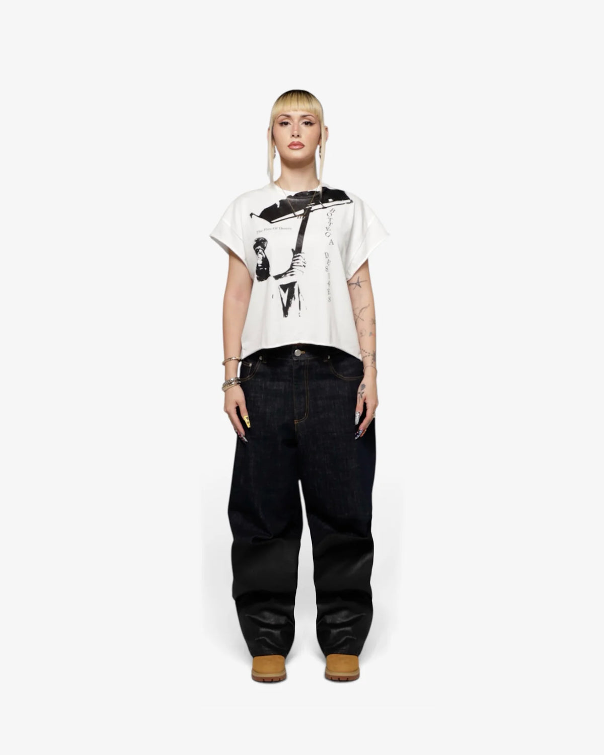Female model in white cut-off tee with black baggy trousers and brown boots