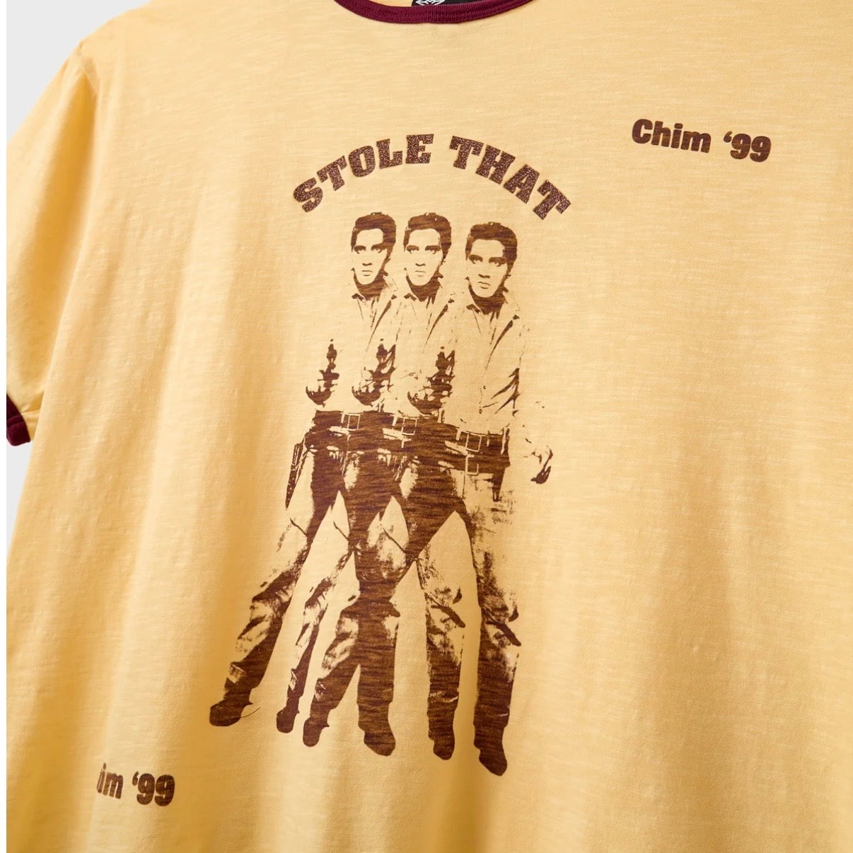 HMDD Stole That T-Shirt, close-up of the brown chest print, three repeated figures under arched STOLE THAT lettering