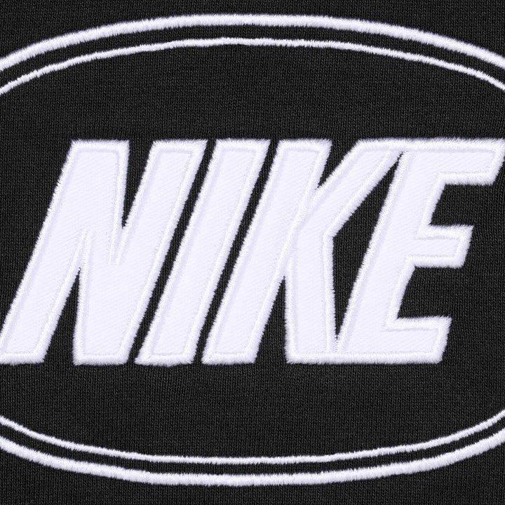 Close-up of the white NIKE applique inside an oval on black fleece