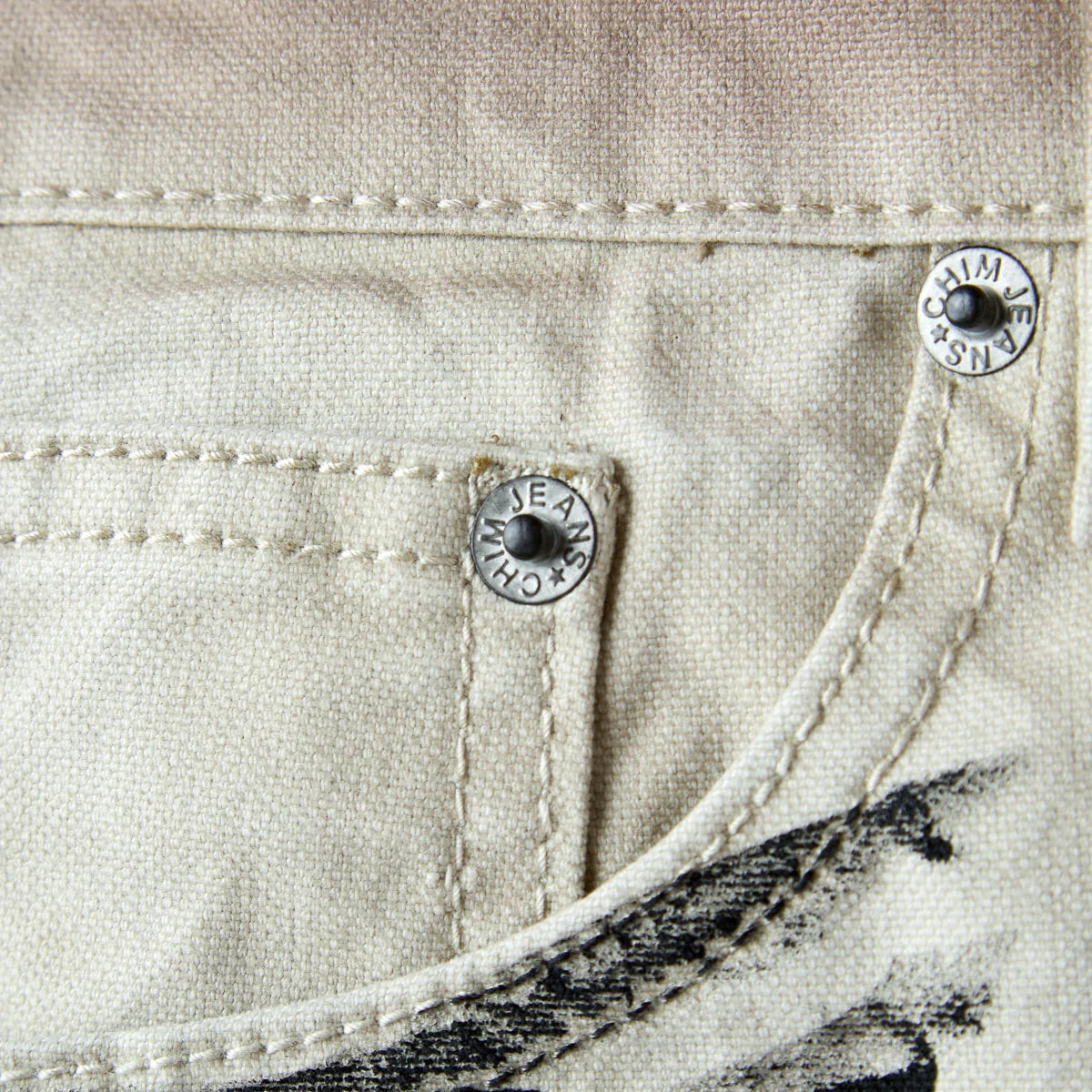 Close-up of the silver shank button stamped CHIM JEANS CO with a star