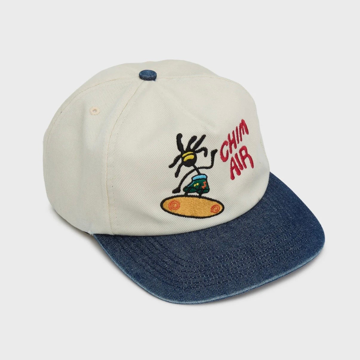 HMDD Chim Air Hat, angled front view showing the embroidered surfing character and red CHIM AIR lettering on cream
