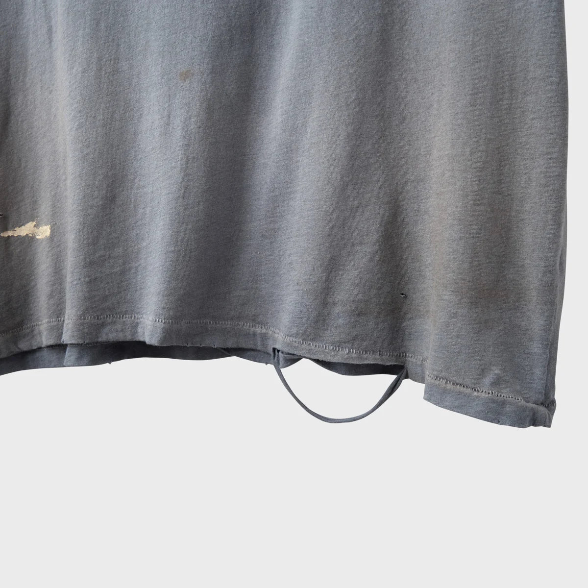 Close-up of the hand-distressed hem on the faded grey tee