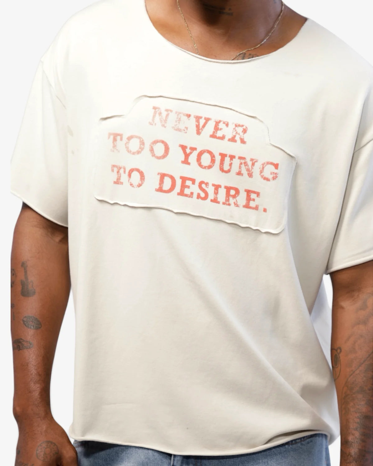 Close torso shot showing the rust-red NEVER TOO YOUNG TO DESIRE applique print