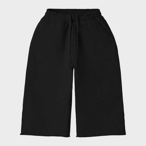 HMDD Blank 3/4 shorts in black fleece with an elastic drawcord waist, wide legs and raw cut hems, front view