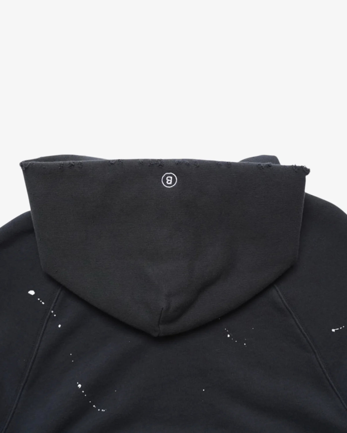 Close-up of the hood back with a small round logo patch and paint splatter