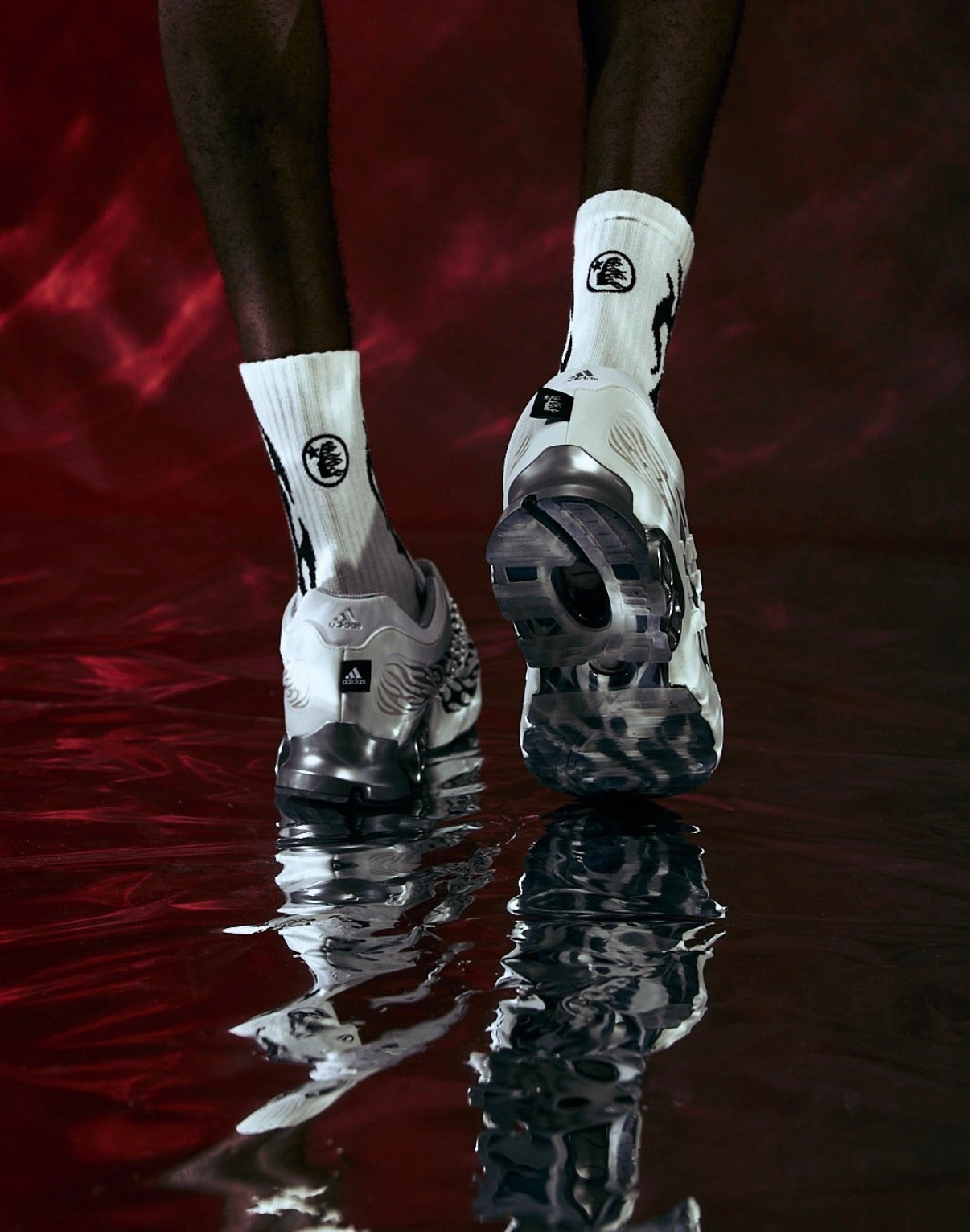 Hellstar Adidas Megaride White, close-up of the shoes on a model's feet, mirrored in the wet floor against a red backdrop