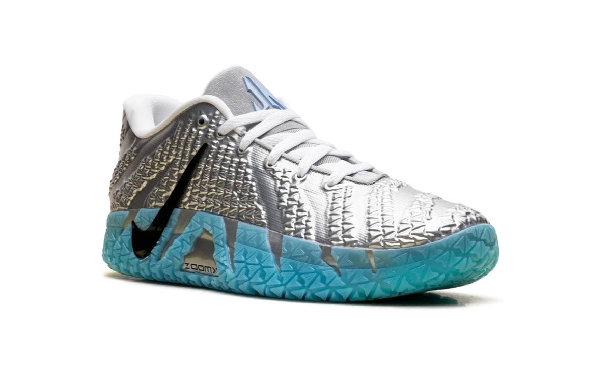 Angled top view of silver Nike Ja 3 with blue triangular Ja logo on tongue top