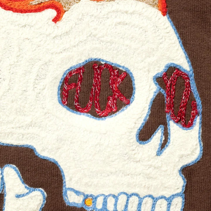 Close-up of the chain-stitched skull on the brown hoodie with red lettering in the eye sockets