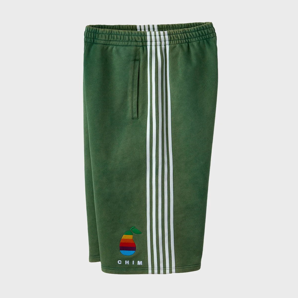 Side view of the green HMDD Pear Tech shorts showing the slash pocket opening and the white striped tape running the full length of the side seam