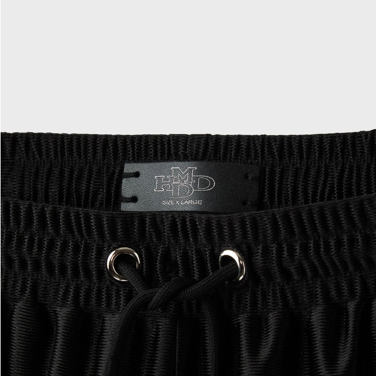 HMDD Black Mixtape Shorts, close-up of the elastic waistband, black drawcord through silver eyelets and a woven HMDD label