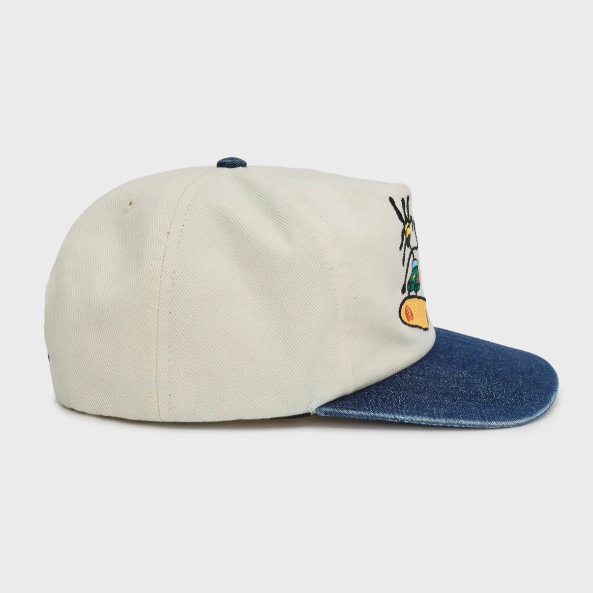 HMDD Chim Air Hat, side view of the cream crown with denim blue brim, blue top button and an embroidered figure