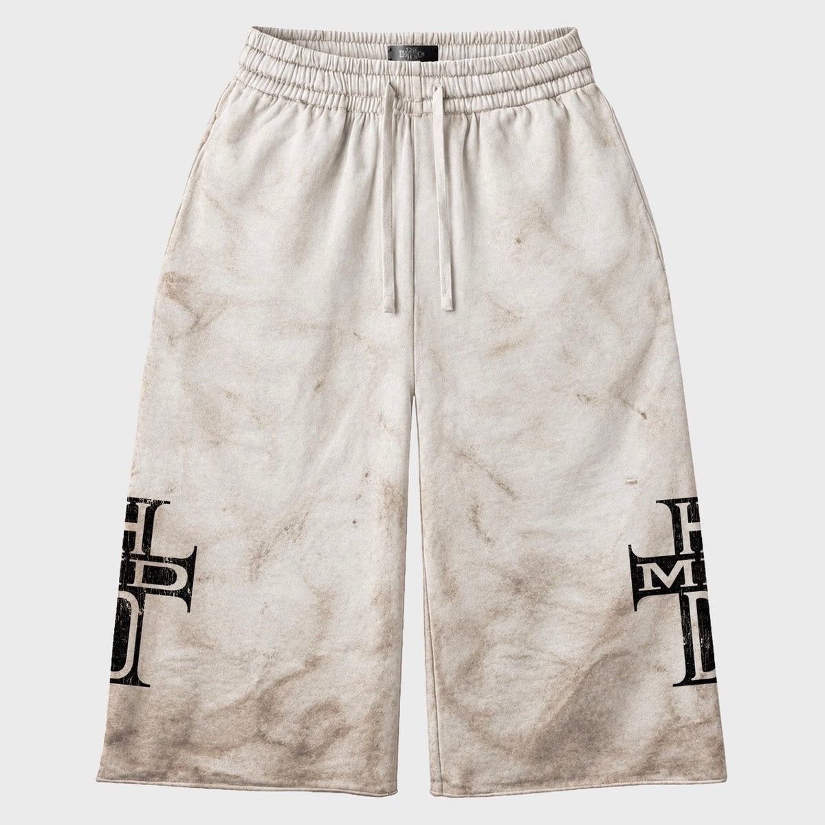 HMDD Holy Cross 3/4 shorts in off-white fleece with a brown mud-wash finish, drawcord waist and black HMDD cross graphics on the lower legs
