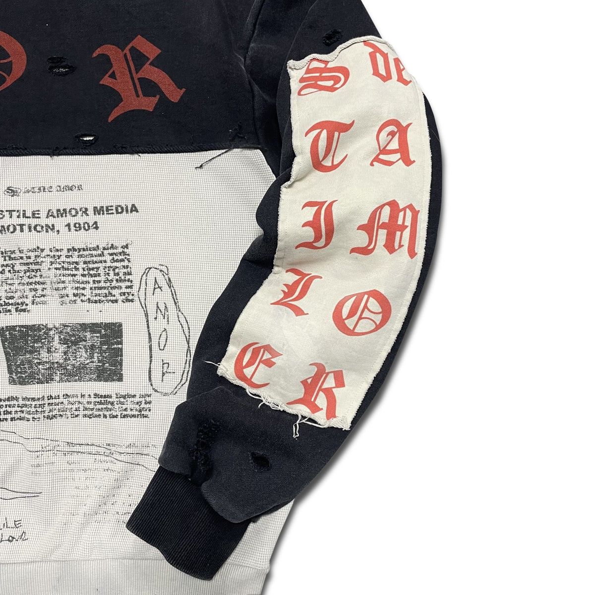 Close-up of the cream sleeve panel with red STILE lettering on the Nero Patch Hoodie